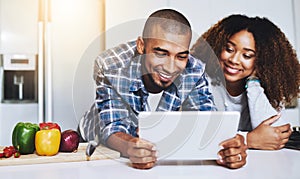 Looking up what to cook. a young couple using a tablet together at home.