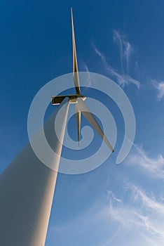 Looking up at a wind turbine, blue sky and white clouds