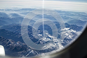 Looking through the window of the plane during the flight to the snow-capped peaks of the Alps of Italy and Austria, the horizon