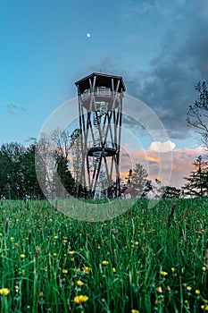 Lookout tower called Na Vetrne Horce at sunset, Broumov region,Czech Republic.Wooden tower with spiral staircase on blooming photo