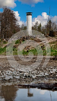 lookout tower in the forest reflected in a puddle on the starse