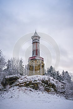 Lookout tower Stepanka on the border of Krkonose and Jizera Mountains. Winter overcast day, sky with clouds, trees