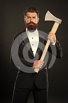 he looks brutal. Brutal gentleman holding axe. Bearded man dark background. Barbershop. Axe shaving. A perfect cut