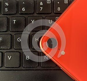 orange smartphone on laptop keyboard