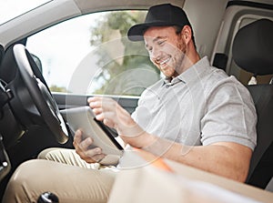 Looks like Im at the right place. Cropped shot of a handsome young delivery man using a tablet while sitting in his van.