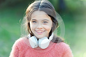 She looks like a music lover. Adorable little girl outdoor. Little girl child wearing headphones. Happy child enjoy