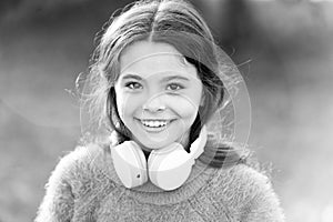 She looks like a music lover. Adorable little girl outdoor. Little girl child wearing headphones. Happy child enjoy