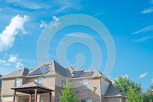 Lookup view covered patio two story suburban residential house with black solar panels installation on shingle roofing sunny cloud photo