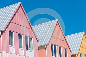 Lookup view of metal roof and gutter on row of new development colorful house with clear blue sky background