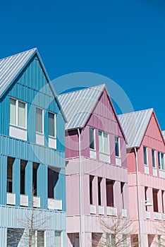 Lookup view of metal roof and gutter on row of new development colorful house with clear blue sky background