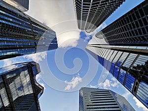 Lookup view of variety of corporate business high-rise skyscrapers buildings with blue bright sky in central business district