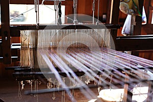 Loom with warp threads under tension interweaving