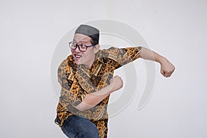 A looney middle aged man about to run in a comical fashion. Exiting the stage in a funny way. Wearing a batik shirt and songkok