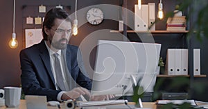 Loop of Middle Eastern businessman typing with computer looking at monitor focused on job in evening in office