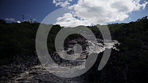 Loopable video of a waterfall and sky with cloud cover amidst lush greenery