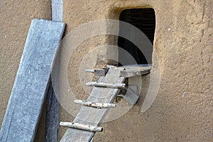 Loophole to the chicken coop made of loam with a homemade wooden chicken ladder