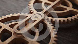 Looping animation of two wooden gears connected by a mechanical shaft.