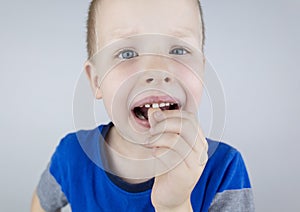 Loose baby teeth. Blond boy touches a milk tooth with his hands and shows how he moves. Stages of growing up
