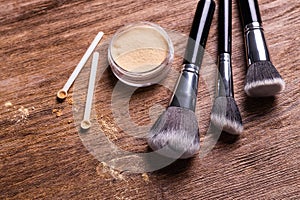 Loose compact mineral powder for face and a brushes for powder and visage on wooden background. Eco friendly and organic