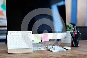 Loose leaf paper calendar standing near computer on desktop closeup