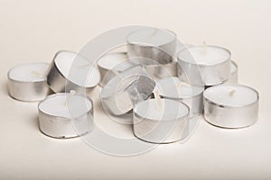 A loose pile of new tea lights on a white background.