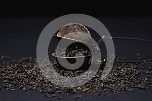 Loose tea on a black background. Loose tea in an old brewing sieve.