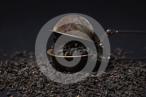 Loose tea on a black background. Loose tea in an old brewing sieve.