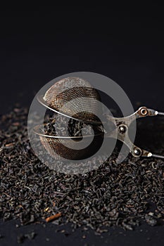 Loose tea on a black background. Loose tea in an old brewing sieve.