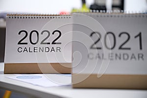 Looseleaf paper calendars for 2021 and 2022 standing on table closeup