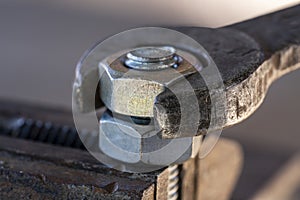 Loosening the nut using a wrench and a vise. Using old spanner wrench and clamp to remove nut from bolt, closeup