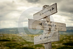 loosing weight now text engraved on old wooden signpost outdoors in nature.