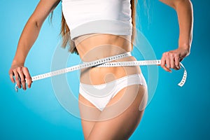 Loosing weight - young woman is measuring her waist