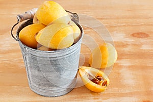 Loquat fruit in bucket on wooden table photo