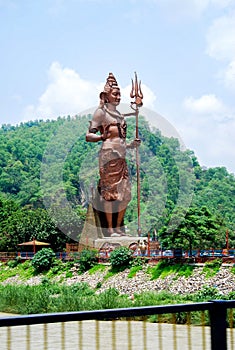 Lord Shiva tall statue with snake near Har ki Pauri Haridwar, Hindu god idol Mahadev at a garden with blue sky background and