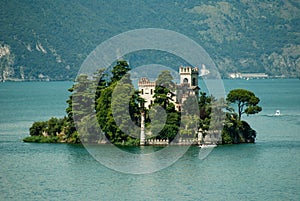 Loreto island in the middle of the Iseo lake with green hills in the background