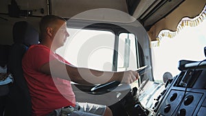 Lorry driver holds arms on a steering wheel and controls the truck riding to destination. Trucker operating a car