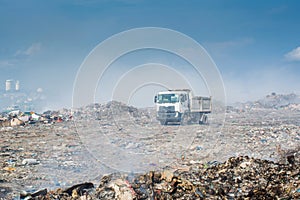 Lorry at the garbage dump full of smoke, litter, plastic bottles,rubbish and trash at tropical island