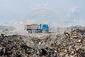 Lorry riding at the garbage dump full of smoke, litter, plastic bottles,rubbish and trash at tropical island