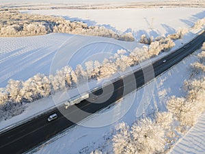 Lorry truck on the road surrounded by winter forest. Aerial view