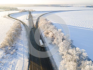 Lorry truck on the road surrounded by winter forest. Aerial view