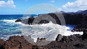 Los Hervideros rocky coast with wavy ocean and volcanos on the background, Lanzarote, Canary Islands, Spain