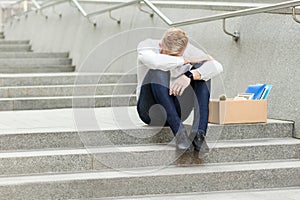 Lose job, young man lost his job, sitting on stairs holding head down, depressed, crying and don`t know what to do in crisis time