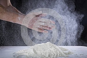 Ð¡lose up of chef human`s hands preparing for kneading the dough on the table, powdering with flour. Making dough by hands at