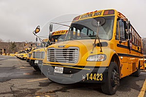 Lose up selective focus frontal view of a school bus fleet at a parking lot.