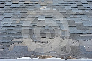 Ð¡lose up view of asphalt shingles roof damage that needs repair.