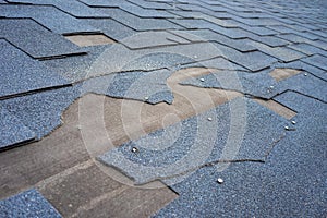 Ð¡lose up view of bitumen shingles roof damage that needs repair.