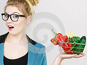 Woman holds shopping basket with vegetables