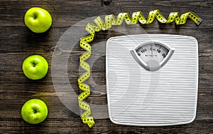 Lose weight concept. Bathroom scale, measuring tape, apples on wooden background top view