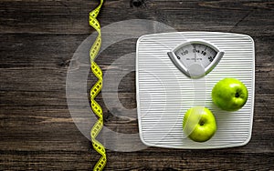 Lose weight concept. Bathroom scale, measuring tape, apples on wooden background top view copyspace