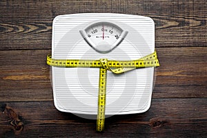 Lose weight concept. Scale and measuring tape on dark wooden background top view